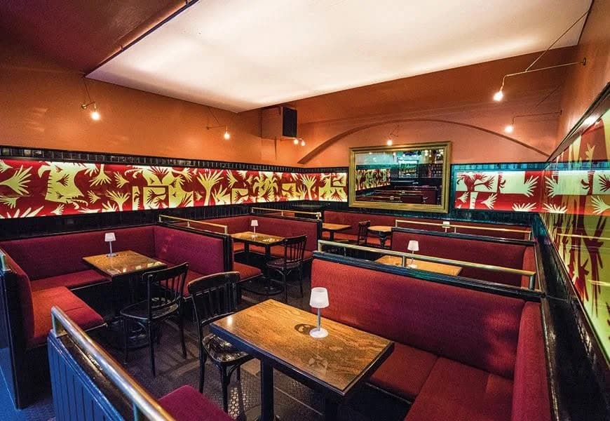 Rote Sitznischen und goldene Palmenmotive im Club Palme in Wien