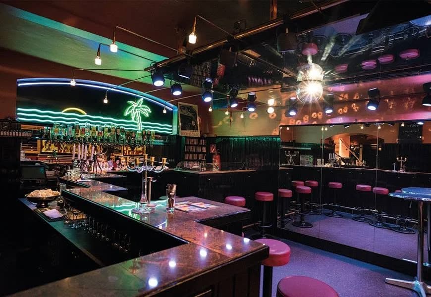 Bar und Discokugel im Club Palme mit leuchtender Neonpalme
